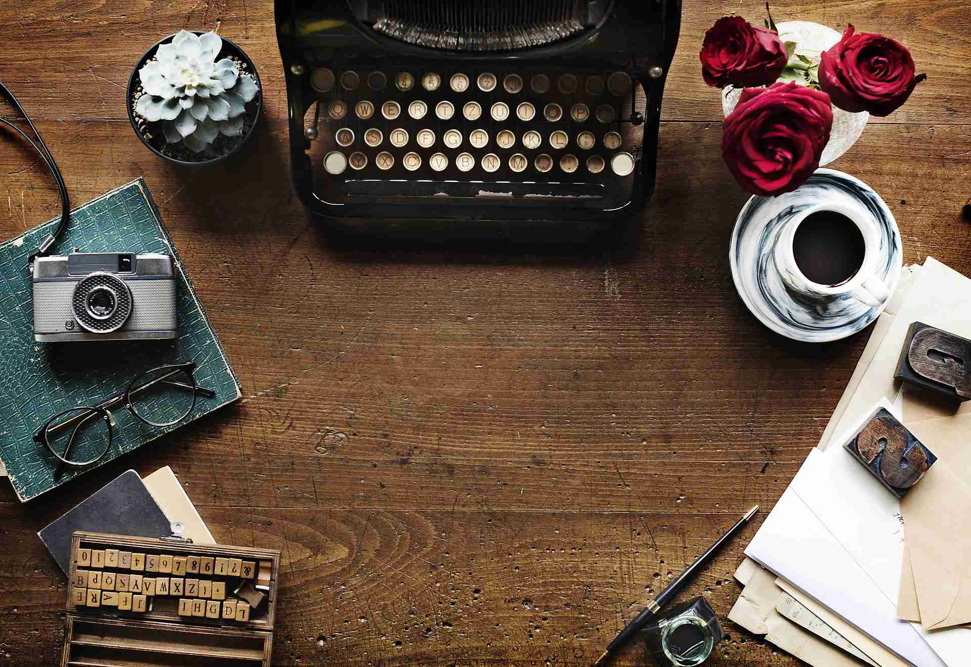 Blick auf eine alte Schreibmaschine, die auf einem Schreibtisch steht, eine Tasse und ein Fotoapparat stehen daneben!